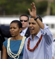 President Barack Obama and first lady Michelle Obama, both wearing leis, greet the crowd at Hickham Air Force Base Thursday in Honolulu.