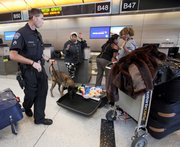 Airport police officer Mike Manahan with his search dog, Baxo, checks a passenger’s bag Tuesday at Tom Bradley International Airport in Los Angeles.