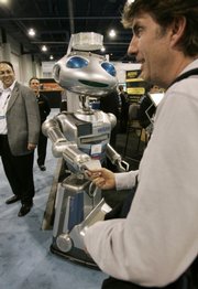 Aan attendee shakes hands with Hoovers Mobile’s remote-controlled Robot, Hoovie, at the International Consumer Electronics Show in Las Vegas In this Jan 11, 2009 file photo. This year’s show will focus on more practical, and affordable, electronic gadgets, including laptop computers and 3D television.