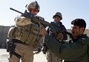 Canadian Police Constable Craig Dickie, left, from Milton, Ontario, demonstrates a gun to an Afghan police officer at a checkpoint in Kandahar City, southern Afghanistan, in this Jan. 17, 2010, file photo. U.S. and Canadian forces are operating on a tight deadline to train a police force that can obstruct a Taliban comeback in Kandahar, which is the place where the militant movement began in the early 1990s.