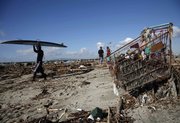 A paddle surfer, left, navigates his way through trash and debris in Seal Beach, Calif., Saturday after a week of storms passed through Southern California.