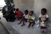 A girl cries after receiving food in an improvised distribution center organized by the United Nations as a U.N. peacekeeper from Brazil kneels to talk to children Sunday in the Cite Soleil neighborhood in Port-au-Prince, Haiti.