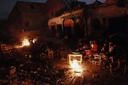 Earthquake survivors sit around a fire Friday in downtown Port-au-Prince. A half-million Haitians who fled their shattered capital after the earthquake are starting to return to a maze of rubble piles, refugee camps and food lines, complicating ambitious plans to build a better Haiti.