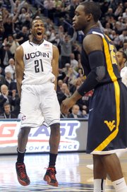 Connecticut’s Stanley Robinson (21) celebrates as West Virginia’s Darryl Bryant looks on near the end of Connecticut’s 73-62 victory Monday in Hartford, Conn.