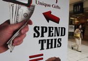 A shopper passes by an advertisement Feb. 16 at NewPark Mall in Newark, Calif. A monthly poll shows consumers’ confidence took a surprisingly sharp fall in February amid rising job worries. The decline ends three straight months of improvement and raises concerns about the economic recovery.