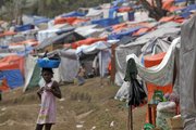 A child carries a pail on her head as she walks inside a camp set up for homeless earthquake survivors Friday in Port-au-Prince.