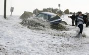 A wave breaks over an occupied car as people attempt to tow it to safety Friday at Camp Ellis in Saco, Maine. The driver left the car as the tide continued to rise, flooding local streets. A third blizzard in less than a month hit the Northeast, leaving more than a million homes and businesses without power.