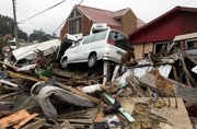 A woman climbs over the debris of her destroyed house Monday in Dichato, Chile. Looting spread in earthquake-leveled parts of Chile on Monday even as army troops were deployed in armored vehicles and on horseback to restore order and protect shipments of food and water.