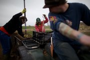 Stephanie Thomas, center, works with Audrey Coleman, left, and Marc Laning, right, to put compost onto freshly planted onions March 17 at Spring Creek Farm.