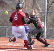 Lawrence High catcher Kristen Bell awaits a throw to home to force out Shawnee Mission North runner Cally Cowan during the fifth inning of the Lions' first game, Thursday, March 25, at Lawrence High School.
