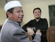 Muhammad Jibriel, right, who was on trial in Jakarta, Indonesia, on charges of helping fund last year’s twin suicide bombings at luxury hotels in Jakarta, speaks with his father, Abu Jibriel, in this March 25 photo. The elder Jibriel is a cleric accused by the U.S. of being a key leader in Jemaah Islamiyah, Southeast Asia’s main extremist network.