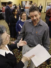 Brad Steele, right, interviews with Betsy Harris, of Express Employment Professionals, at a National Career Fair on Thursday in Cincinnati. The number of newly laid off people signing up for unemployment benefits rose sharply for the second straight week, suggesting that jobs are still hard to come by even as the economic recovery gains traction.