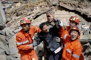A survivor waves after he was rescued Thursday from rubble of a collapsed building after an earthquake Wednesday in Yushu county, western China’s Qinghai province. China poured rescue crews and equipment into a mountainous Tibetan region Thursday in a bid to find survivors more than a day after strong earthquakes killed more than 700 people and injured thousands.