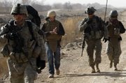 Associated Press reporter Chris Torchia takes notes as he walks with U.S. soldiers of the 4th Battalion, 23rd Infantry Regiment, 5th Brigade, 2nd Infantry Division during a dismounted patrol Feb. 15 in the Badula Qulp area, west of Lashkar Gah in Helmand province, southern Afghanistan.
