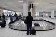 A woman waits for her luggage in the east terminal at Lambert St. Louis International Airport. Most carriers now charge around $25 for the first checked bag and $30 for a second bag. The airlines have size and weight requirements, too.