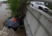 A car is pinned against a tree and a bridge Sunday in Nashville, Tenn. Severe storms dumped heavy rain on Tennessee for the second straight day, leaving at least 15 dead in Tennessee and northern Mississippi.