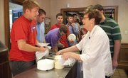 Phi Kappa Psi housemother Esther Wolfe talks across the dinner buffet line with Overland Park senior Rob Conard at the fraternity house. Tradition at the house is to escort Wolfe to dinner and allow her to eat and be seated first. Wolfe has served as housemother for almost 13 years, and among her duties is teaching a class on etiquette to the freshman members.
