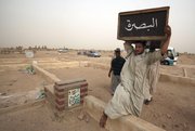 A man carries the coffin of a bombing victim for burial Tuesday in the Shiite city of Najaf, Iraq, 100 miles south of Baghdad. Iraqi forces beefed up checkpoints, conducted house-to-house searches and rifled through cars Tuesday looking for suspects behind a devastating string of attacks across the country that killed 119 people a day earlier.
