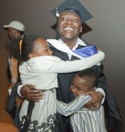 Chief warrant officer Ari Jean-Baptiste is hugged by his children Pria, 9, and Noah, 7, after their father was hooded in a master’s degree hooding ceremony Saturday at Kansas University. Jean-Baptiste is one of six soldiers in the Wounded Warrior Educational Initiative at KU who are graduating this weekend.