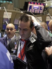 Trader Gregory Rowe, right, works Thursday on the floor of the New York Stock Exchange. The Dow Jones industrial average fell 376 points, its biggest one-day point drop since February 2009, and all the major indexes were down well over 3 percent.