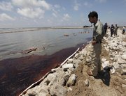 Louisiana Gov. Bobby Jindal looks at encroaching oil Friday as he tours a land bridge built by the Louisiana National Guard to hold back oil from the Deepwater Horizon oil spill in Grand Isle, La.