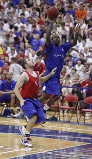 Blue team guard Tyshawn Taylor lofts a pass over red team guard Jordan Juenemann during the alumni scrimmage Wednesday, June 16, 2010 at the Horejsi Center.