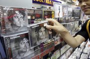 Ryosuke Kawada, an employee of Tower Records, shows a Michael Jackson CD in Tokyo in this June 26, 2009 file photo. Jackson’s estate has earned more than $250 million in the year since he died.