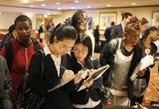 Flora Guan, left, and Jessica Yang, right, recent graduates of San Francisco State University, fill out forms to take part in surveys with Fieldwork San Francisco on June 28 at a National Career Fair in San Francisco. The unemployment rate fell to 9.5 percent, its lowest level in almost a year.
