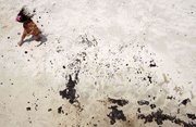 An unidentified girl avoids puddles of oil on the beach Friday in Gulf Shores, Ala. Oil from the Deepwater Horizon incident is expected to come ashore over the Fourth of July weekend.