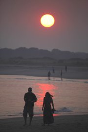 People gather along Cape May Beach on Tuesday in Cape May, N.J., to watch the sunset. The East Coast broiled under an unforgiving sun Tuesday as record-toppling temperatures soared to 100 or higher in several cities, utility companies cranked out power to cool the sweating masses and the unlucky sought any oasis they could find.