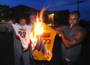 Cleveland Cavaliers fans, from left, Josh Hall, Rob Hose, and Mike Adams set fire to LeBron James jerseys on Thursday in Akron, Ohio, after James announced he is leaving the Cavaliers to join the Miami Heat.