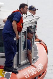 Members of the Coast Guard look Thursday for two missing tour boat passengers on the Delaware River in Philadelphia. The passengers’ amphibious craft in which they were riding was struck and sunk by a barge Wednesday.