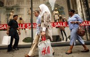 Shoppers leave an H&M clothing store Thursday in New York. Stores steepened discounts more than planned in June to help drive recession-scarred customers into the malls to buy summer merchandise. But shoppers spent cautiously amid escalating job worries, resulting in modest gains for many merchants.