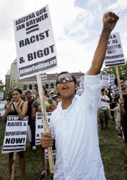 Jose Briceno, of Cambridge, Mass., raises his fist during a rally against Arizona’s immigration law Saturday in Boston. Arizona Gov. Jan Brewer is attending the annual meeting of the National Governors Association this weekend in Boston.