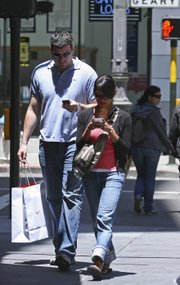 A couple text message while walking June 29 in San Francisco. While using a cell phone while driving has triggered the most alarm bells and prompted laws in several states, experts say pedestrians are also suffering the consequences of mobile distraction, including tripping on curbs, walking into traffic, even stepping into manholes as they chat or type while walking.