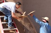 Marcos Martinez, left, and Steven Torres, parishioners of San Francisco de Asis Church in Ranchos de Taos, N.M.,apply mud to the thick adobe walls of the church June 14 as part of an annual ritual that has been done for nearly 200 years.