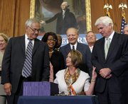 House Speaker Nancy Pelosi, D-Calif., center, reaches out to Rep. Barney Frank, D-Mass., left, and Sen. Christopher Dodd, D-Conn., right, after signing the financial reform legislation during an enrollment ceremony Thursday on Capitol Hill in Washington.