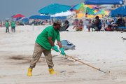 An oil cleanup worker rakes the sand Sunday in Orange Beach, Ala. BP hopes to keep using its giant stopper to block oil from reaching the Gulf of Mexico until it plugs the blown-out well permanently.