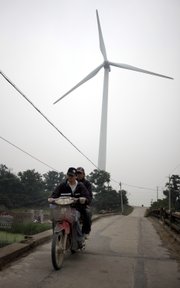 Men ride a motorcycle near the wind power generator in Nantong, east China’s Jiangsu province, in this June 2, 2009, file photo. China has overtaken the United States as the world’s largest energy consumer, the International Energy Agency said Tuesday. China immediately questioned the calculation.