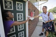 hands the day’s mail to Raina Washington as he makes his daily deliveries Friday in Akron, Ohio. The veteran mailman has gained a reputation for three times delivering people from life-threatening situations while on the job delivering mail. Last week, he gave CPR to a man along his Akron route who wasn’t breathing and whose lips were turning blue.