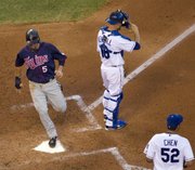 Minnesota’s Michael Cuddyer, left, scores on a single by J.J. Hardy as Kansas City catcher Jason Kendall and starting pitcher Bruce Chen (52) wait for the throw. The Twins routed the Royals again, 11-2, on Tuesday in Kansas City, Mo.