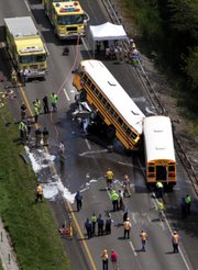 Emergency workers respond to an accident involving two school buses, a tractor-trailer and a pickup truck on Thursday near Gray Summit, Mo. The National Transportation Safety Board is examining the accident, a process that will take up to 18 months.