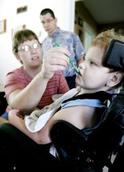 Beth Schneweis feeds her son Christopher, 5, some yogurt inside their Great Bend home as Christopher’s dad, Mike, looks on in this July 27 photo. The couple are hoping to raise money for Christopher have a stem cell procedure for his cerebral palsy at a clinic in Germany.