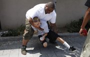 Anthony Morris, 27, top, a chaser and security guard at the Learning Works! Charter School, and Edgar Rodriguez, 17-year-old high school dropout, joke around during their lunch break July 21 in Pasadena, Calif. The chasers round up the students, covering every excuse they use to not attend school.