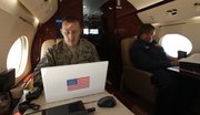 U.S. Air Force interpreter Tech. Sgt. Paul Shoop, left, works on his computer, as Russian Air Force Col. Alexander Vasiliev sits across the aisle as they fly aboard a civilian airplane playing the role of a hijacked airliner Sunday. The exercise is a first-of-its-kind joint exercise between the United States and Russia to test their coordinated response to a potential international hijacking.