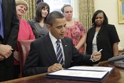 President Barack Obama signs a $26 billion jobs bill Tuesday to protect 300,000 teachers and other nonfederal government workers from election-year layoffs in the Oval Office at the White House in Washington. Behind the president are, from left, Christina Romer, chair of the Council of Economic Advisers, and three out-of-work teachers: Amanda VanNess, Toledo, Ohio; Shannon Lewis, Romney, W.Va.; and Rachel Martin, Richton Park, Ill.