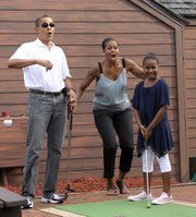 President Barack Obama and first lady Michelle Obama react as their daughter Sasha gets a hole-in-one on the first hole as they play miniature golf Saturday at Pirate’s Island Golf in Panama City Beach, Fla. The Obamas are spending the weekend in Florida.