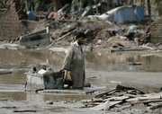 A flood survivor wades through mud as he salvages belongings Saturday in Azakhel, near Nowshera, northwest Pakistan. A case of the deadly waterborne disease cholera has been confirmed in Pakistan’s flood-ravaged northwest, and aid workers expect there to be more, the U.N. said Saturday.