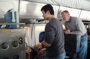 KU graduate student and research assistant Lei Shi, left, consults Electrical Engineering Professor Chris Allen, technical director of CReSIS, on radar settings during an October 2009 research flight.