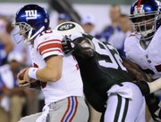 New York Giants quarterback Eli Manning escapes a tackle attempt by the New York Jets’ Shaun Ellis, center, as the Giants’ Kareem McKenzie, right, tries to help Manning. Manning left the game with a gash to his head that required 12 stitches Monday at the New Meadowlands Stadium in East Rutherford, N.J.
